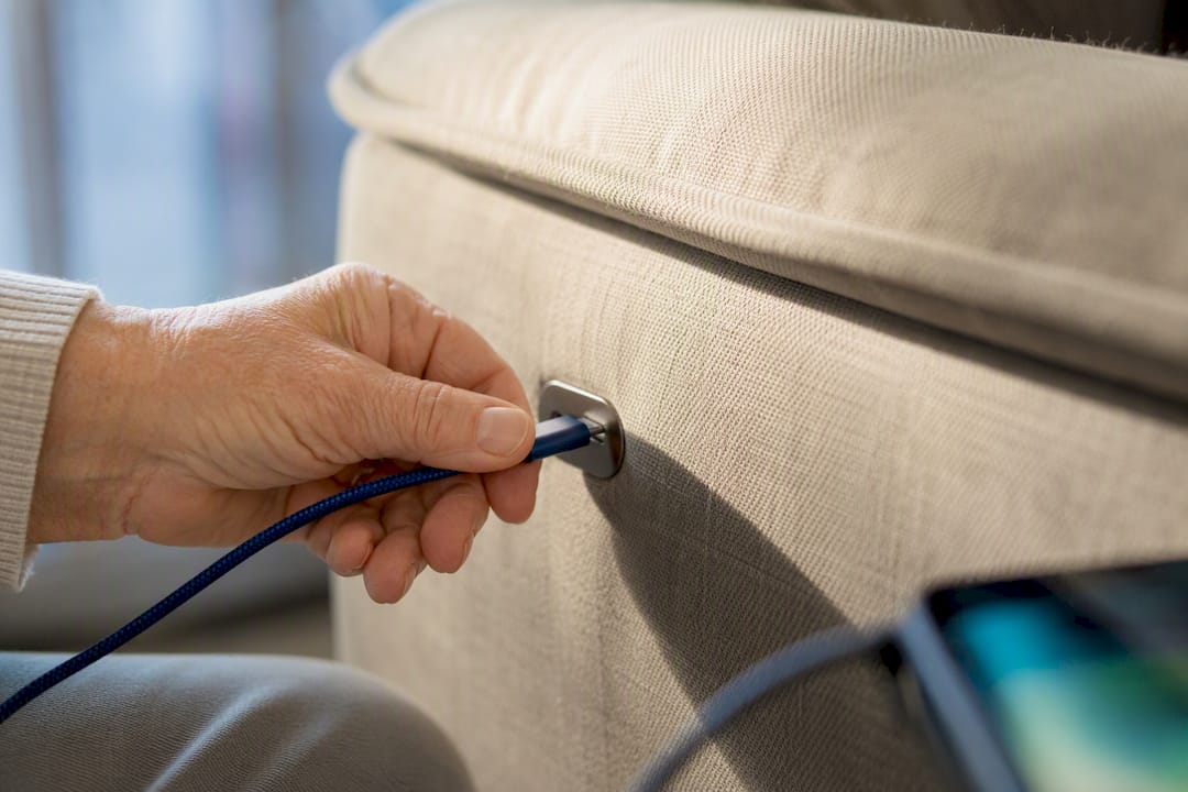 Hand steekt laadkabel in USB-poort