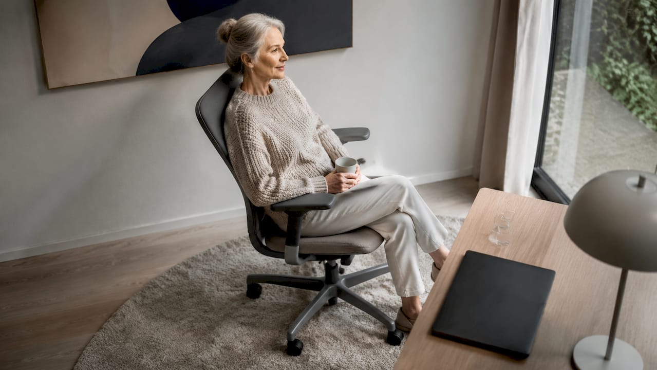 Een oudere dame zit comfortabel op een ergonomische stoel.