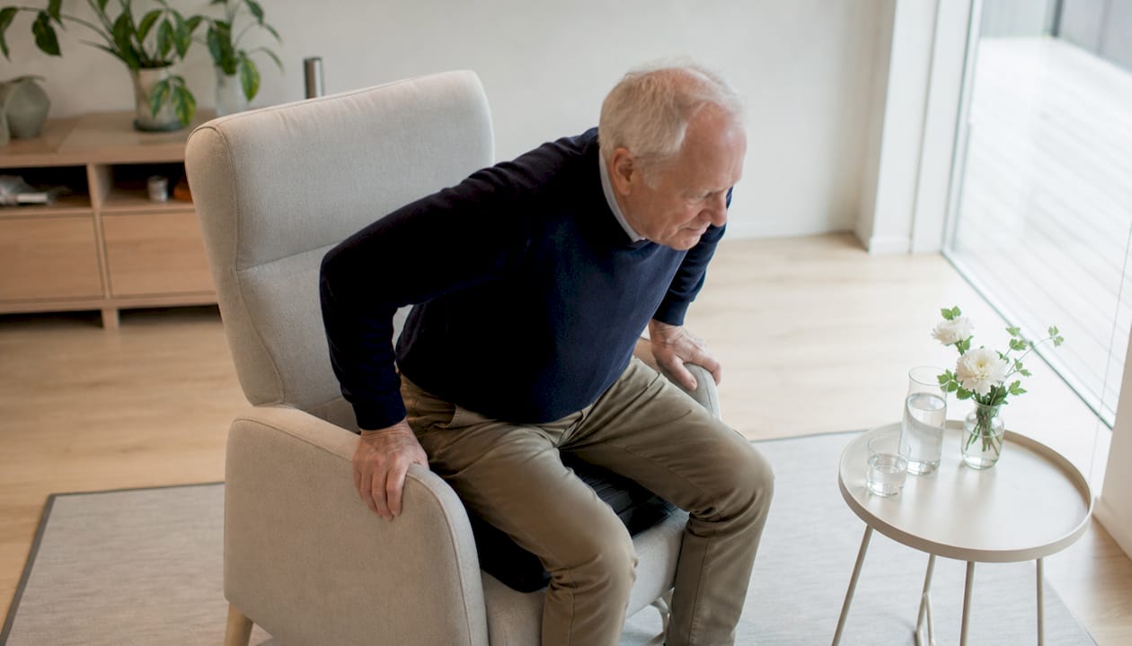 Een oudere man die opstaat met behulp van een sta-op kussen.