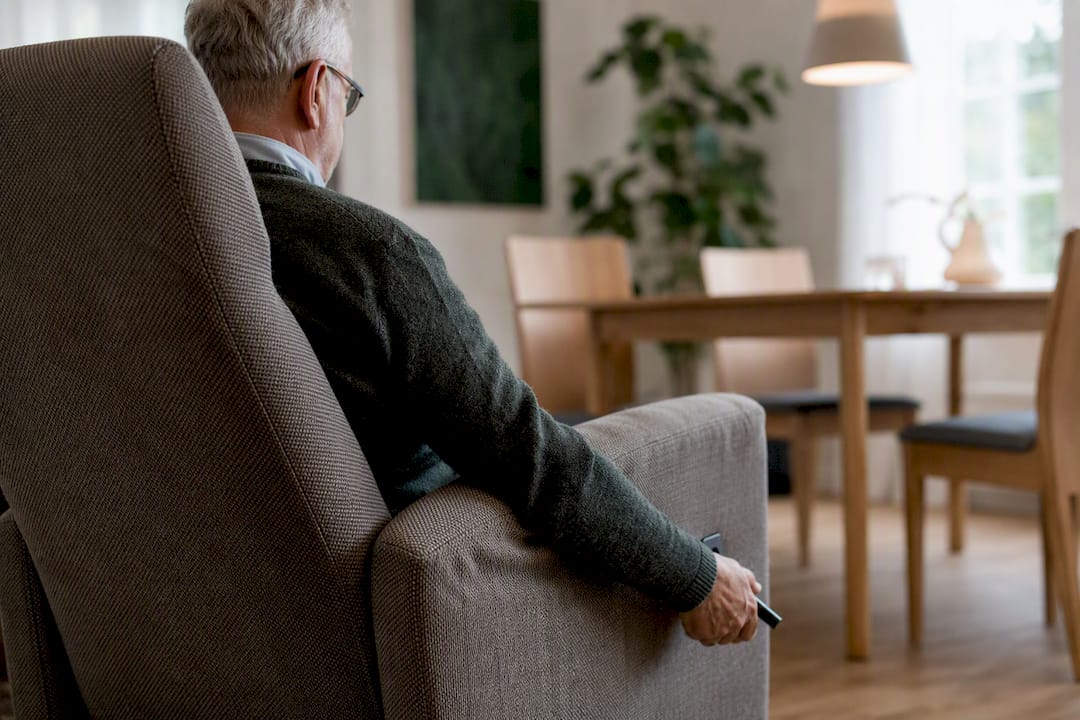 Oudere hand die de hendel van een sta-op stoel verstelt